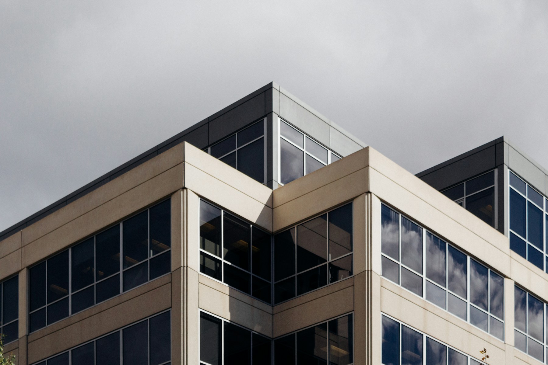 Angle d'un immeuble de bureaux contemporain, bardage clair et bandeaux vitrés sombres